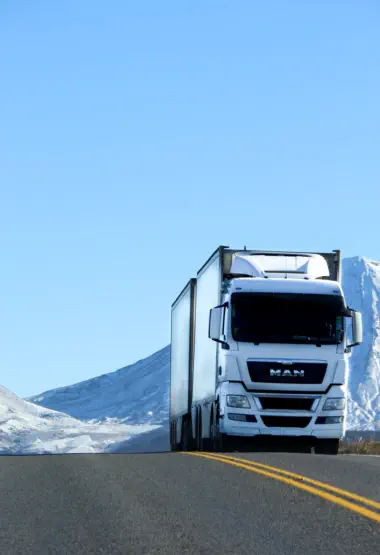 White logistics truck on a snow-lined highway